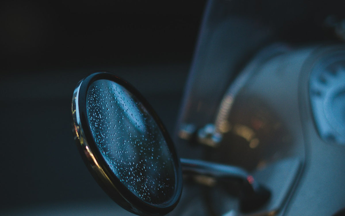 Retrovisor y manillar de una moto con gotas de agua. Foto: Julien Riedel / Unsplash